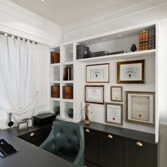 an office with white walls, black desk and shelves filled with framed pictures on the wall