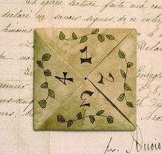 an origami envelope with leaves and birds on it sitting on top of a piece of paper