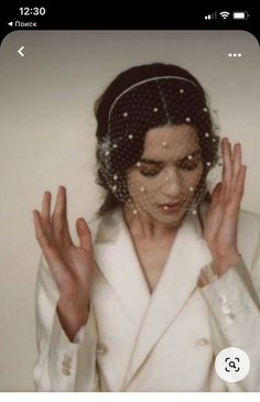 a woman wearing a veil and holding her hands in front of her face with both hands