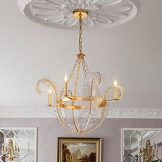 a chandelier hanging from the ceiling in a room with paintings on the wall