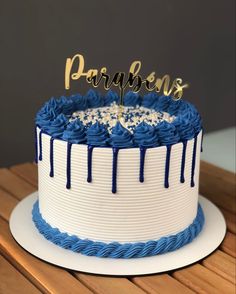 a blue and white cake with the word paragons on top is sitting on a wooden table