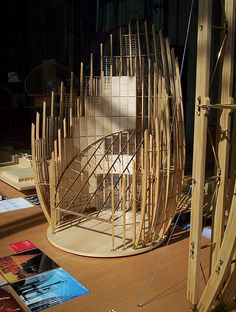 a sculpture made out of wooden sticks on top of a table next to books and magazines