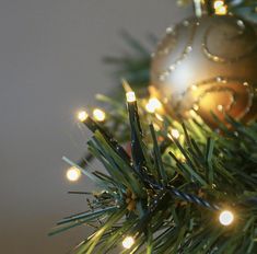 an ornament hanging from the top of a christmas tree with lights on it