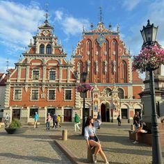 people are sitting on benches in front of an old building