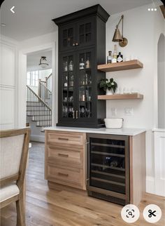 a kitchen with black cabinets and wooden flooring is shown in this image, there is a wine rack on the wall