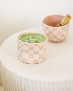 two small cups sitting on top of a white table