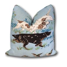 a blue pillow with two dogs on it and birds flying over the dog's head