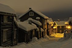 a snowy street lined with wooden houses at night