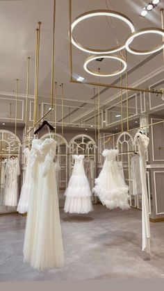 wedding gowns are on display in a room with circular lights and chandeliers