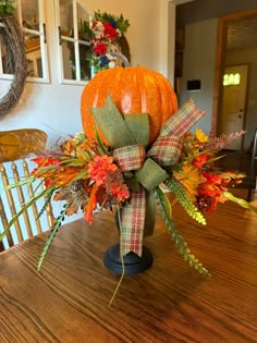 an arrangement of fall flowers and pumpkins on a table