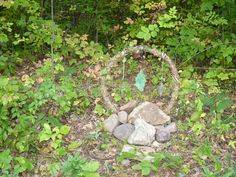 a rock garden in the middle of some bushes and trees, with a circle made out of rocks