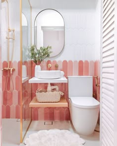 a white toilet sitting next to a sink in a bathroom under a large round mirror