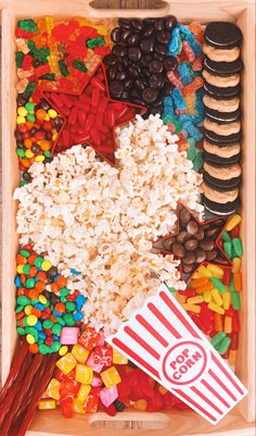 a wooden box filled with lots of candy and cookies next to a movie popcorn bag