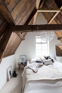 an attic bedroom with wooden beams and white bedding