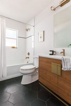 a bathroom with black tile flooring and white walls, along with a wooden cabinet