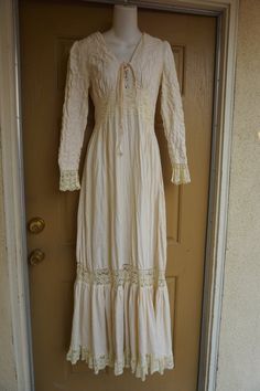 Size 13 Gunne Sax prairie dress fits smaller - please see measurements.  Zips in the back with adjustable tie at the back of the waist. Condition - has one small spot mid skirt to the side - see last photo.Measurements taken across front lying flat18" across front armpit to armpit14" across front of waist (ties tighter)59" length Elegant Fitted Long Sleeve Peasant Dress, Bohemian Cream Maxi Dress For Fall, Fitted Beige Peasant Dress, Beige Fitted Peasant Dress, Lace Trim Maxi Dress For Fall, Maxi Dress With Lace Trim For Fall, Beige Long Sleeve Maxi Dress With Lace Trim, Fall Maxi Dress With Lace Trim, Long Sleeve Lace Maxi Dress With Lace Trim