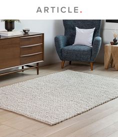 a living room with a blue chair and white rug in front of a wooden dresser