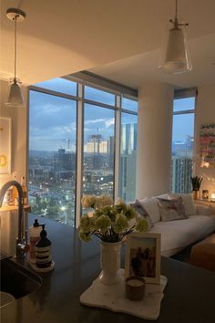 a living room filled with furniture next to tall windows and a view of the city