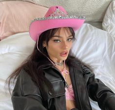 a woman wearing a pink cowboy hat on top of a bed