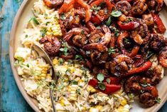 a plate filled with rice, meat and veggies next to a spoon on a table