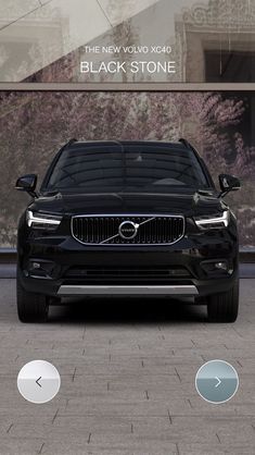 the front end of a black volvo car parked in front of a building with windows