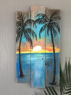 two palm trees painted on wooden planks with the sun setting in the distance behind them