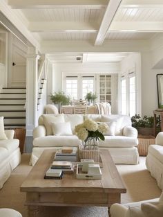 a living room filled with white furniture and lots of pillows on top of it's couches