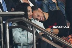 a man and woman hugging each other while standing on an escalator at a sporting event