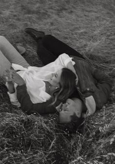 black and white photograph of two people laying on the ground in grass with one person holding his head up