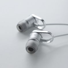 two silver headphones sitting next to each other on a white surface with wires running through them