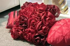 a bouquet of red roses sitting on the floor next to a pillow and pillows in front of a mirror