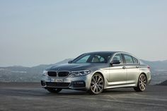 a silver bmw car parked on top of a parking lot next to a mountain range