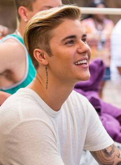 a young man with a tattoo on his arm smiles at the camera while sitting down