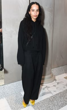 a woman standing in front of a mirror wearing black clothing and yellow shoes with long hair