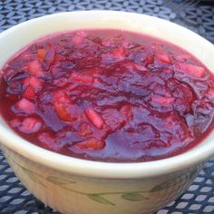 a white bowl filled with red sauce on top of a blue tablecloth covered table