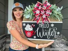 a woman holding up a sign that says hello winter with snowflakes and coffee