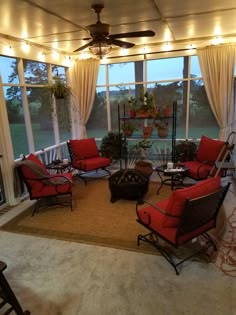 a living room filled with lots of furniture under a ceiling fan and windows covered in curtains