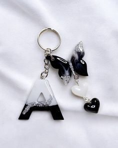 two black and white letters are attached to key chains on a white sheet with hearts