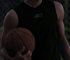 a man holding a basketball in his right hand and wearing a black shirt with the number 50 on it