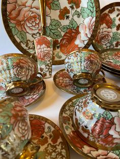 a table topped with lots of fancy plates and bowls filled with flowers on it's sides