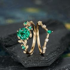 two gold rings with green stones and leaves