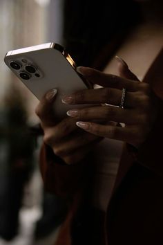 a close up of a person holding a cell phone in their hands and looking at the screen