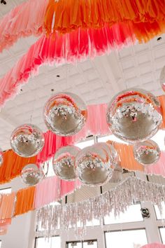 the chandelier is hanging from the ceiling with pink and orange tassels