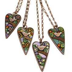 three heart shaped stained glass pendants hanging from chains on a white background with flowers and leaves