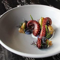 an octopus is garnished with fruit on a white plate