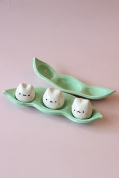 three small white eggs sitting on top of a green leaf shaped tray next to each other