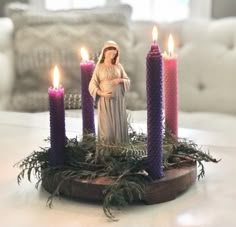 a nativity scene with three candles and a figurine in the middle on a table