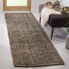 a large rug is in the middle of a room with a chair and potted plant