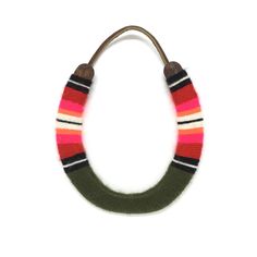 a green, pink and white striped necklace on a brown leather cord against a white background