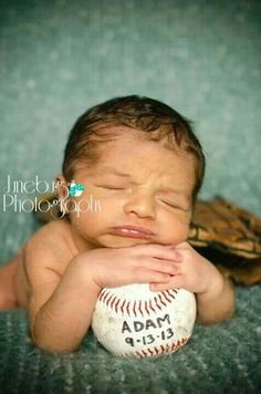 a baby laying on top of a baseball next to a glove